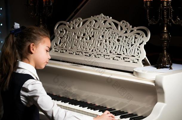 小的女孩演奏指已提到的人钢琴在旁边烛光.