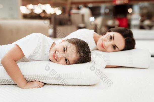 微笑的小的女孩和美丽的母亲紧抱枕头采用商店