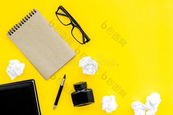 作家办公室书桌和笔记簿,墨水,笔和眼镜黄色的波黑