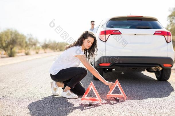 女人配售<strong>警告三角</strong>形在旁边破碎的汽车