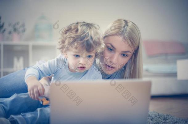 妈妈和婴儿儿子观察漫画向便携式电脑.