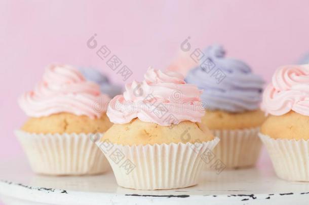 纸杯蛋糕和粉红色的和紫罗兰甜奶油酱st和ing向彩色粉笔钉