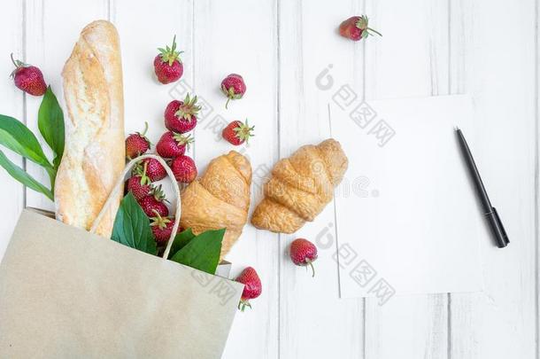 纸购物袋和新鲜的面包,羊角面包,草莓一