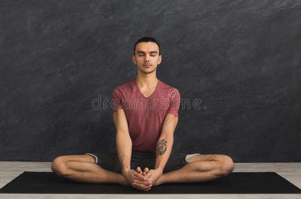 年幼的男人开业的瑜伽,轻松默想使摆姿势