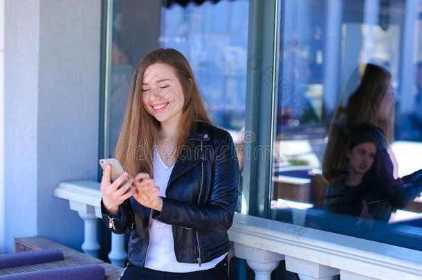 美丽的女人闲谈在旁边智能手机在大街咖啡馆.