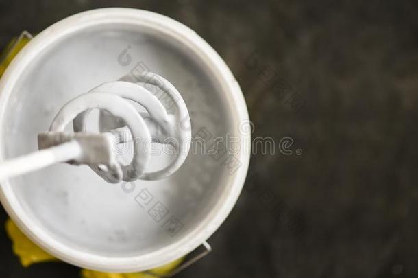 宽叶短桨搅拌器越过指已提到的人水桶和白色的颜料为墙,DoItYourself自己动手做器具
