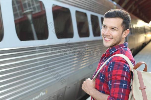 英俊的上下班往返的人微笑的在期间等候为他的火车