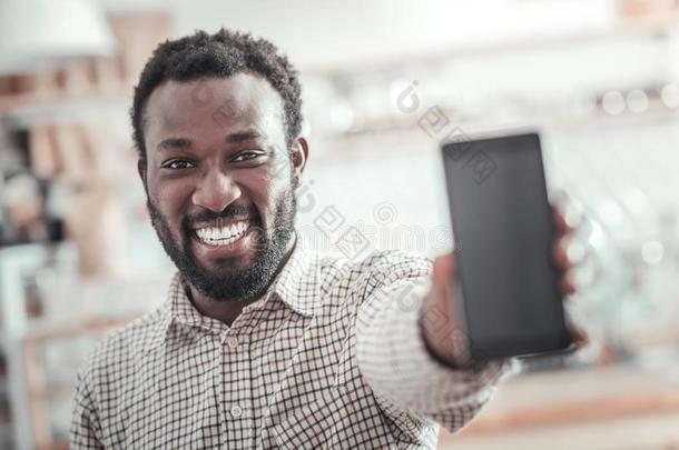 幸福的积极的男人展映他的智能手机