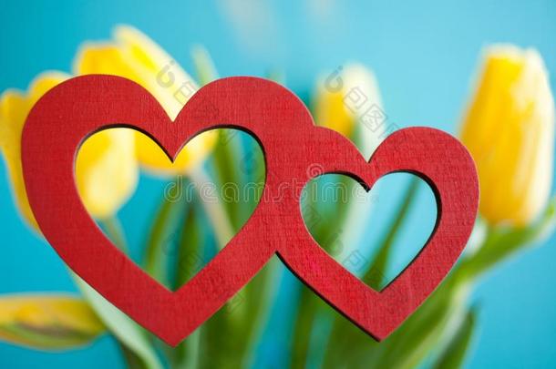 两个红色的心向blur红色的花的背景关于黄色的郁金香机智