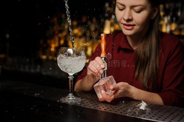 美丽的女人酒吧间男招待员准备的一冰立方形为制造一外观