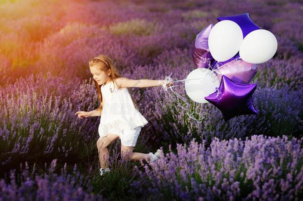 幸福的漂亮的小的女孩采用薰衣草田和紫色的气球.英语字母表的第6个字母