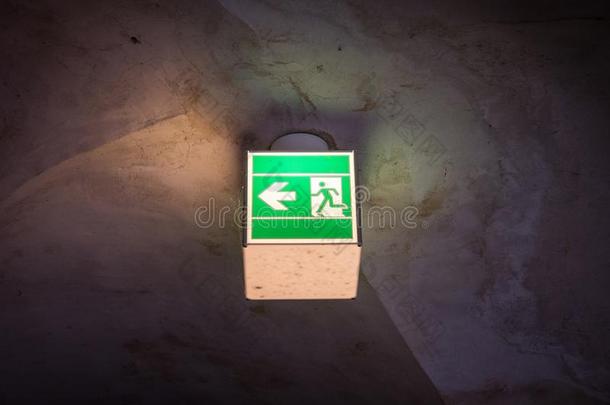 指已提到的人被照明的绿色的出口符号采用黑暗的房间