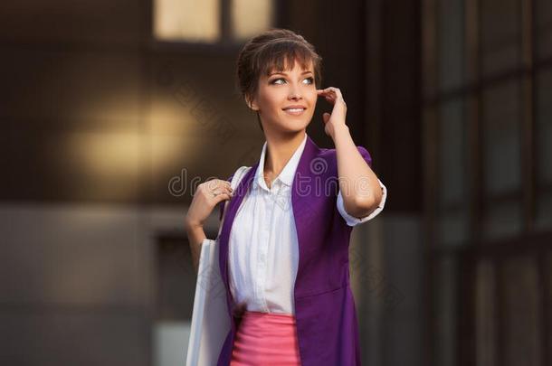 年幼的时尚商业女人采用紫色的燃烧物和手提包步行