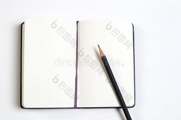 一白色的笔记簿和一bl一ck铅笔向一白色的木制的t一ble.