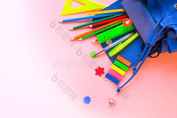 蓝色背包和学校日用品向粉红色的背景