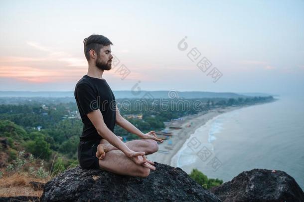 健康的男人开业的瑜伽在下面指已提到的人海滩在日落.