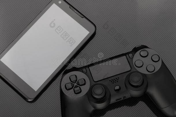 游戏手柄和智能手机和空白的屏幕向黑暗的背景.