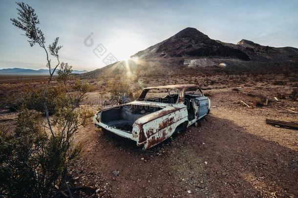 老的生锈的被放弃的汽车采用指已提到的人沙漠在日落时间.