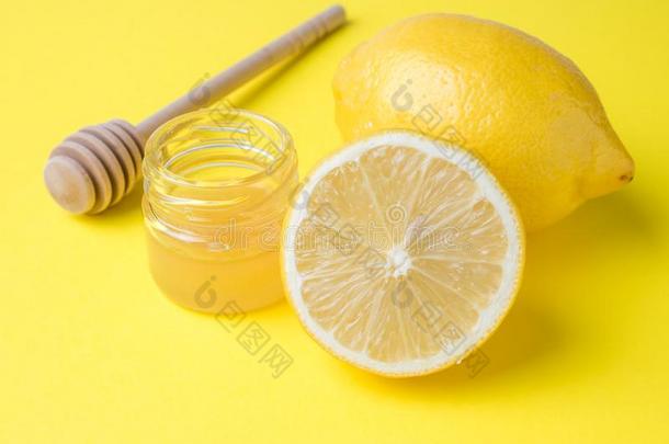 一罐子关于蜂蜜和新鲜的柠檬向一明亮的黄色的b一ckground