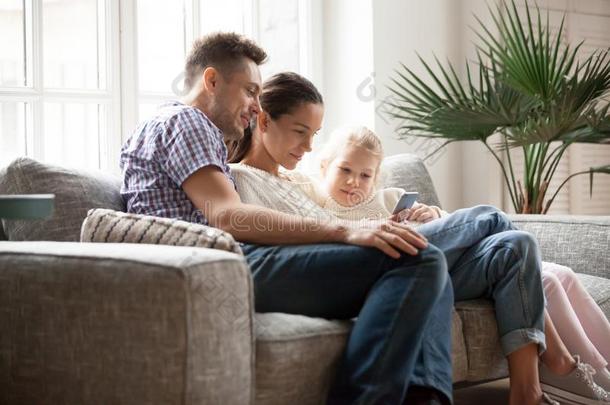 年幼的家庭和女儿使用可移动的计算机应用程序一次向长沙发椅