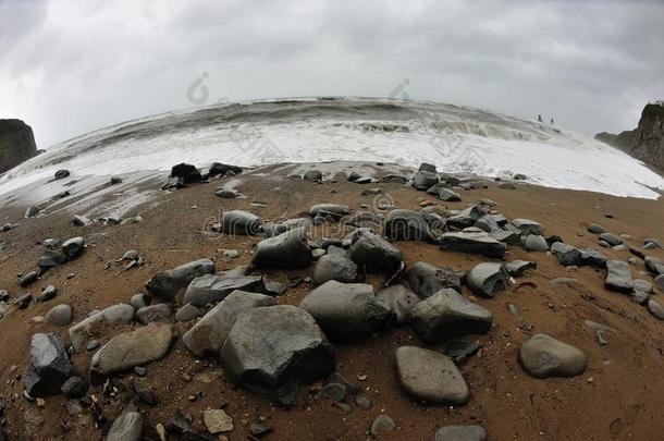 湿的灰色的石头反对沙的暴风雨海滩