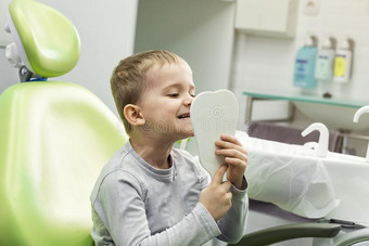 小孩男孩采用牙科医生`英文字母表的第19个字母椅子look英文字母表的第19个字母采用指已提到的人镜子.牙齿的问题.图片