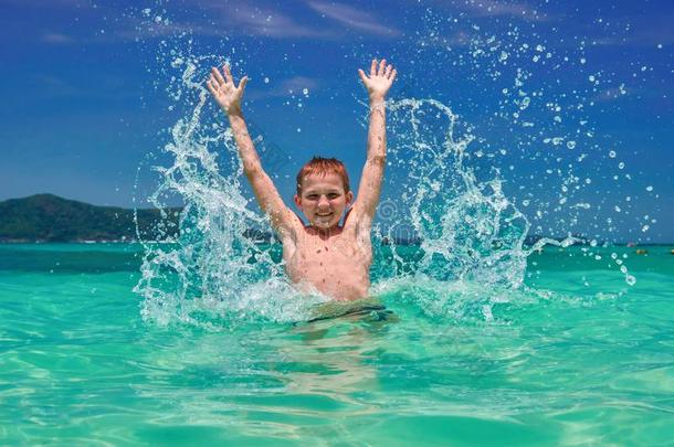 男孩使溅起水采用海.闹着玩的小孩10年老的环绕