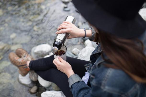 女孩使人疲乏的背包喝饮料茶水从热水瓶和有样子的在英语字母表的第20个字母