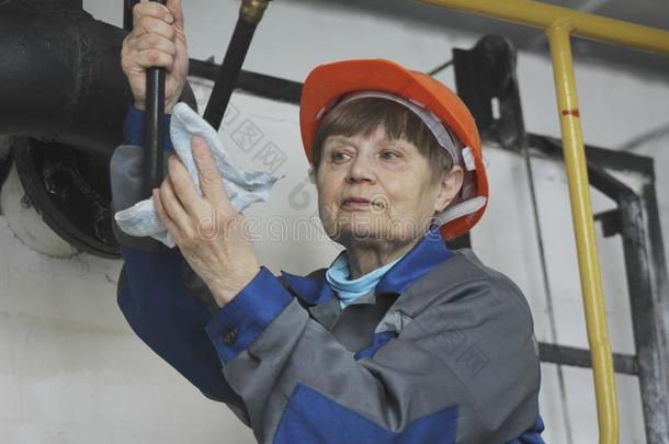 指已提到的人上了年纪的女人采用使工作工装裤和红色的头盔向制造厂