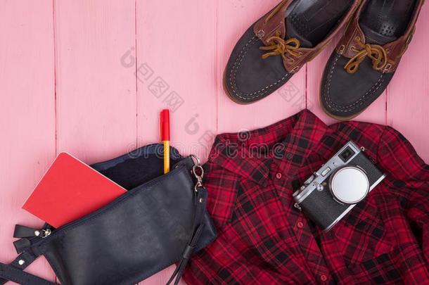 袋,照相机,鞋子,衬衫,笔记给装衬垫向粉红色的木制的背景