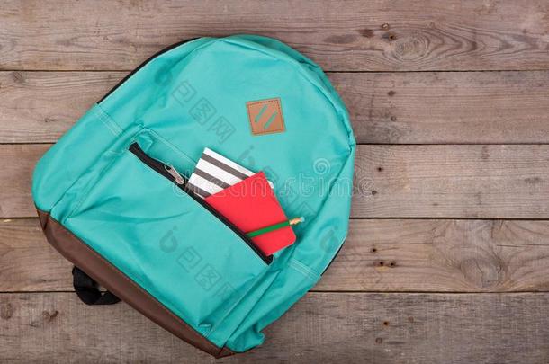 背包和学校日用品便条簿,铅笔向棕色的木制的帐单
