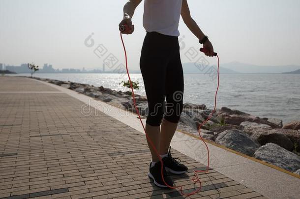 健康女运动家出行向用于跳跃的粗绳向海岸