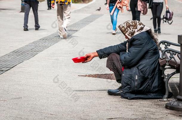 饥饿的无家可归的乞丐女人乞讨为钱向指已提到的人都市的大街我