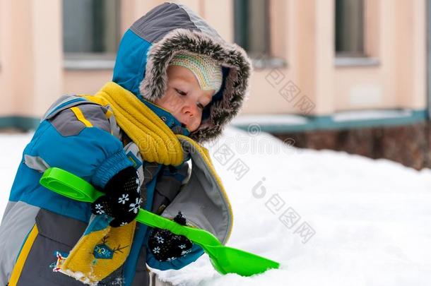 小的男孩演奏和雪和铁锹