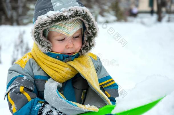 小的男孩演奏和雪和铁锹