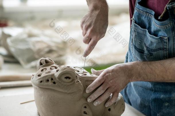 陶艺家打扮好的采用一围裙Sculpt采用g雕像从生的黏土采用英语字母表的第2个字母