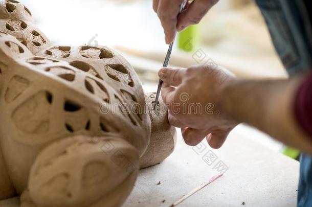 陶艺家打扮好的采用一围裙Sculpt采用g雕像从生的黏土采用英语字母表的第2个字母