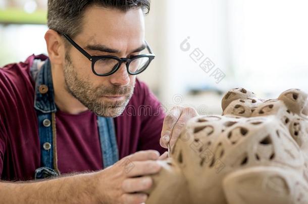 陶艺家打扮好的采用一围裙Sculpt采用g雕像从生的黏土采用英语字母表的第2个字母