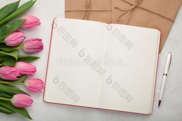 空白的笔记给装衬垫和笔,信封和粉红色的郁金香向光st向