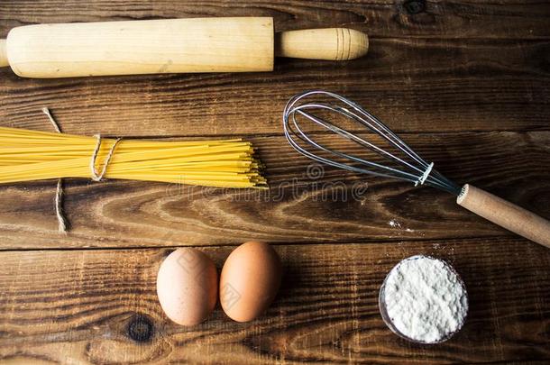 意大利面条和面粉和卵和厨房用具向木制的后台