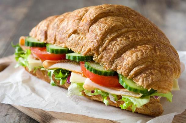 羊角面包三明治和奶酪,火腿和蔬菜向木制的帐单