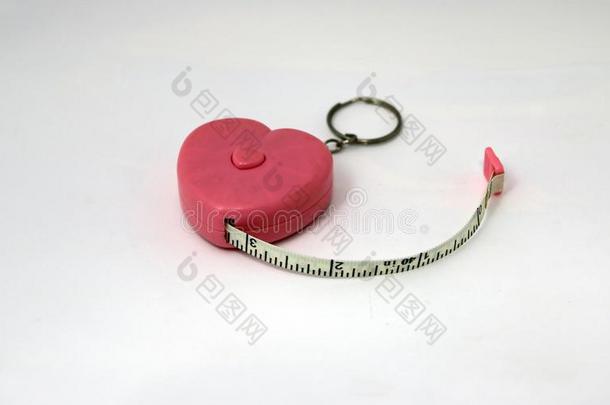 钥匙链子粉红色的塑料制品心测量带子向白色的背景.