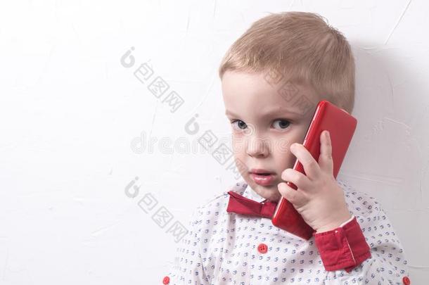一小的严肃的男孩是（be的三单形式谈判一红色的sm一rtphone.