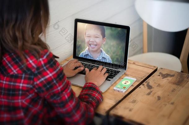 年幼的女人坐有样子的她儿子照片从便携式电脑在期间放松点