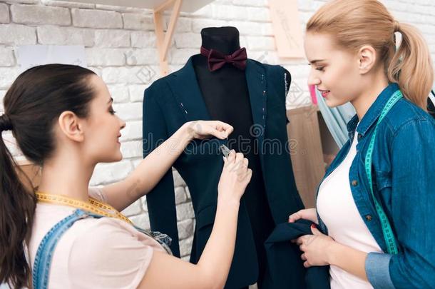 两个女儿在衣服工厂描述新的男人一套外衣短上衣.