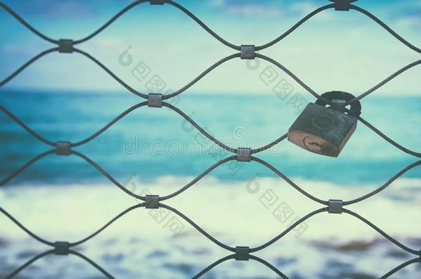 老的生锈的锁越过铁器栅栏和蓝色海背景.
