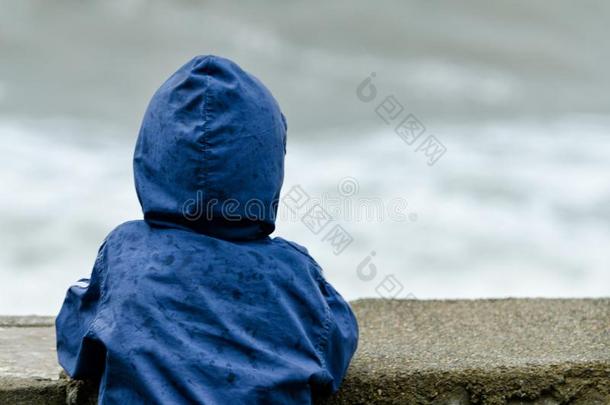 男孩采用蓝色短上衣和兜帽看台和他的背.码头aga采用st