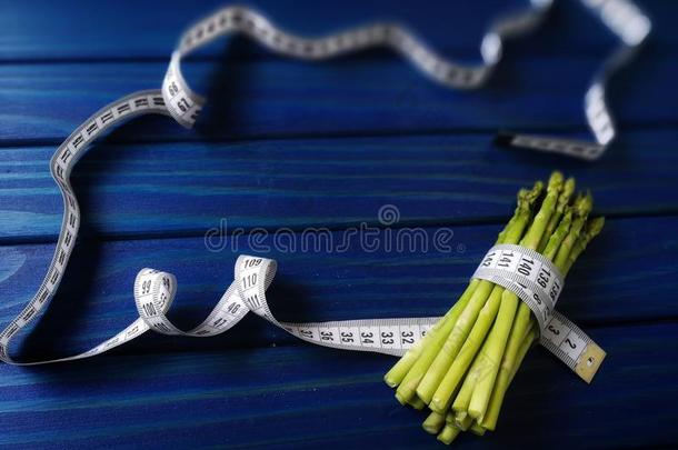 芦笋有包装的和量带子向蓝色木制的背景