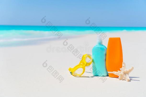 防晒霜瓶子,眼镜,海星向白色的沙海滩
