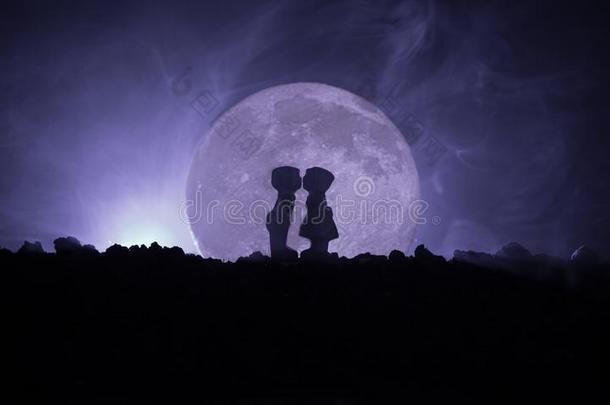 轮廓关于对接吻的在下面满的月亮.家伙接吻女孩手